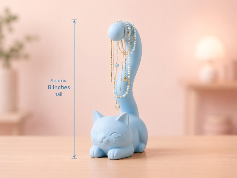 May include: A light blue cat-shaped jewelry holder with a long, curved tail designed to display necklaces. The figure stands approximately 8 inches tall and features a smooth, matte finish with a smiling feline face and pointed ears.