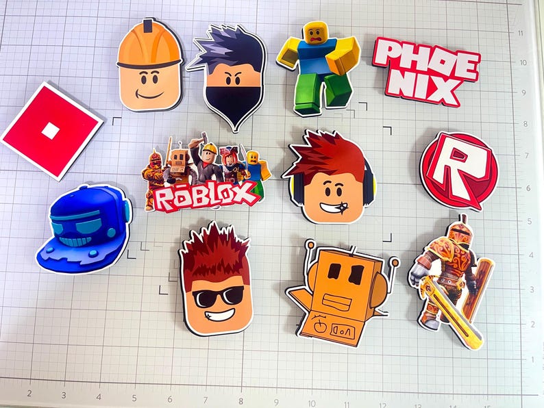 Set of 12 Roblox cupcake toppers featuring popular characters, logos, and icons from the game. Includes layered paper designs with vibrant colors, perfect for gamer-themed birthday parties, cupcakes, and dessert table decor. Ideal for Roblox fans and video game celebrations.