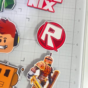 Set of 12 Roblox cupcake toppers featuring popular characters, logos, and icons from the game. Includes layered paper designs with vibrant colors, perfect for gamer-themed birthday parties, cupcakes, and dessert table decor. Ideal for Roblox fans and video game celebrations.