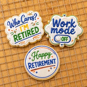 May include: Three decorated sugar cookies with retirement-themed messages. One cookie says "Who Cares? I'M RETIRED" in blue, yellow, and green. Another says "Work mode OFF" in blue. The third says "Happy RETIREMENT" in green and blue.