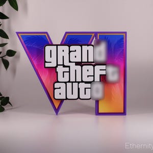 May include: A colorful sign featuring the text "grand theft auto" in a bold, white font. The sign has a vibrant gradient background of pink, purple, and orange, with a blue border. The sign is likely a decorative item.