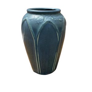 May include: A dark blue ceramic vase with a textured, leaf-like design. The vase has a rounded body and a narrow opening.
