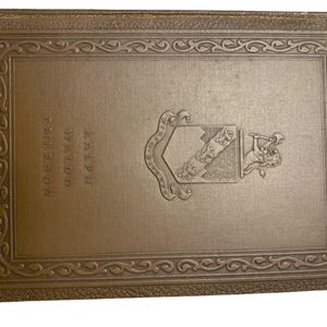 May include: A vintage book cover in a muted gold tone. The cover features embossed text reading "Ralph Waldo Emerson" and an ornate emblem. The border is decorated with a repeating scroll design, suggesting a classic or antique literary work.