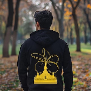 Könnte beinhalten: Ein schwarzer Hoodie mit einem gelben Aufdruck einer Blume und eines Gebäudes auf der Rückseite.