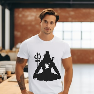 May include: White t-shirt with a black silhouette of Shiva, a Hindu deity, sitting in meditation with a trident behind him. The silhouette has a white image of a bull inside.