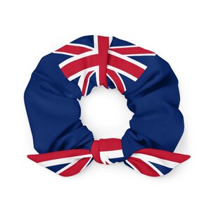 May include: A blue scrunchie with a red and white Union Jack flag design. The scrunchie is made of a soft fabric and has a knotted bow detail. This hair accessory is perfect for adding a touch of patriotic flair to any hairstyle.