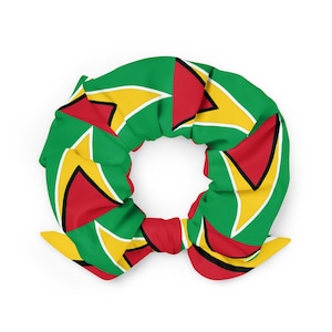 Könnte beinhalten: Ein Haargummi aus Stoff mit einem sich wiederholenden Muster der Nationalflagge von Guyana. Das Design besteht aus grünen, gelben, roten, weißen und schwarzen geometrischen Formen, die in einem kreisförmigen, gerafften Stil angeordnet sind.