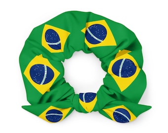 May include: A green scrunchie featuring the Brazilian flag design. The scrunchie has a repeating pattern of the Brazilian flag, with yellow diamond shapes containing a blue circle with white stars, set against a green background.