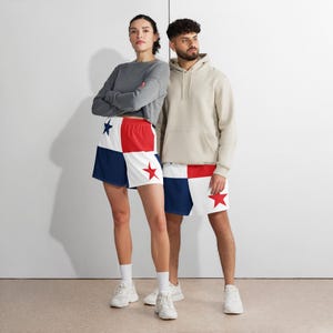 May include: Two people wearing matching shorts with a red star and a blue star on a white background. The shorts have a red and blue color block design. One person is wearing a gray long-sleeve shirt, and the other is wearing a beige hoodie.
