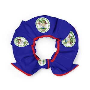 May include: A blue scrunchie with red trim and multiple Belize flag emblems. The scrunchie is made of a soft fabric and is designed to hold hair in place. The Belize flag features a coat of arms within a white circle.
