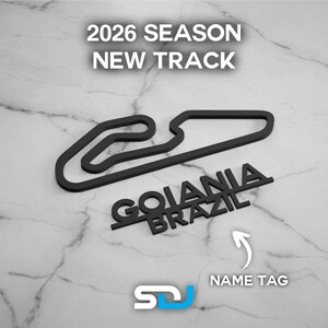 以下が含まれることがあります： 「2026 SEASON NEW TRACK」と「GOIANIA BRAZIL」の文字が入った黒いレーストラックの輪郭。白い矢印が「NAME TAG」を指しています。「SDJ」のロゴが左下にあります。背景は大理石模様です。