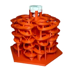 Puede incluir: Laberinto naranja impreso en 3D con una parte superior blanca y una base hexagonal. El laberinto tiene varios niveles y caminos sinuosos.