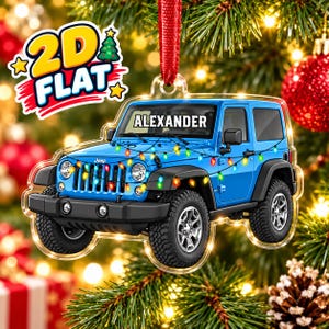 May include: A flat, two-dimensional blue Jeep ornament featuring the name ALEXANDER printed on the windshield. The vehicle is decorated with a string of colorful Christmas lights draped across the hood and front, suspended by a red ribbon.