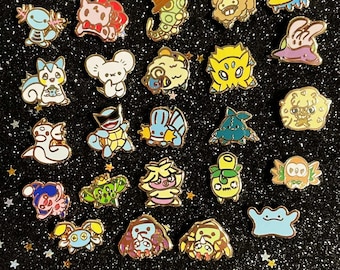 May include: A collection of colorful enamel pins featuring various cartoon characters. The pins are in different shapes and sizes, with gold-colored metal borders. The background is black with scattered gold star-shaped glitter.