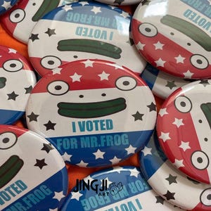May include: A collection of red, white, and blue circular buttons with a cartoon frog wearing a green hat and the text "I Voted for Mr. Frog".