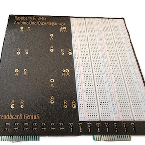 May include: A black breadboard with gold-colored connectors and a white breadboard with rows of holes. The breadboard is labeled "Raspberry PI 3/4/5 Arduino Uno/Duo/Mega/Giga" and "Breadboard Genius".