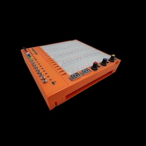 Può includere: Una breadboard arancione con una griglia bianca, una fila di fili colorati e due display digitali. La breadboard viene utilizzata per progetti elettronici.