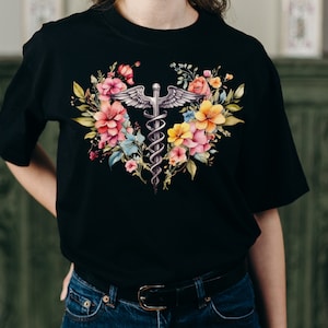 May include: Black t-shirt with a floral design featuring a caduceus, a symbol associated with medicine and healthcare.