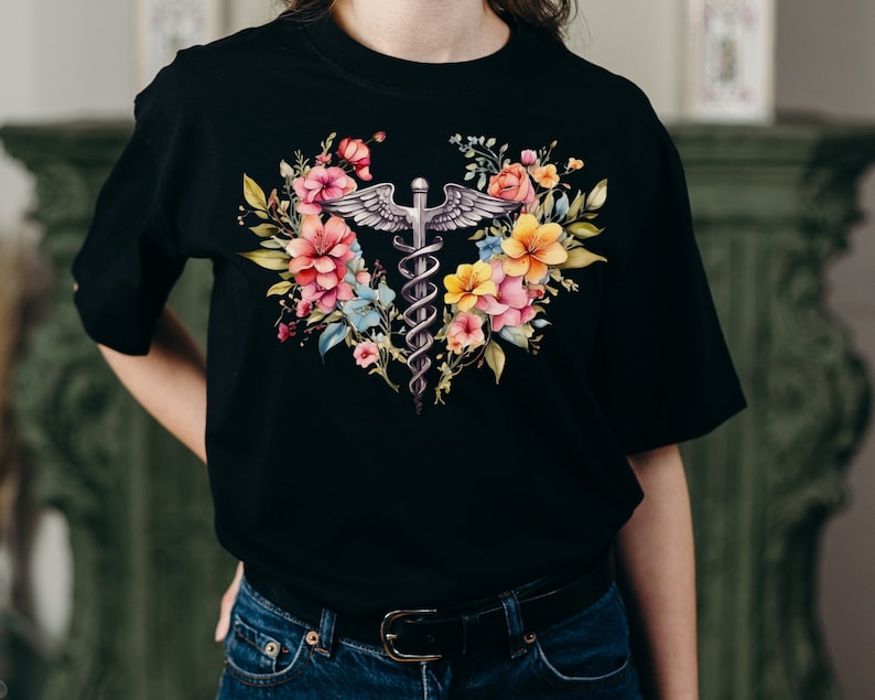 May include: Black t-shirt with a floral design featuring a caduceus, a symbol associated with medicine and healthcare.