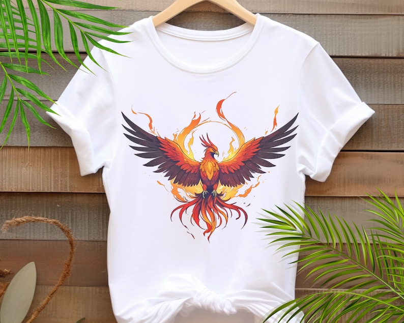 May include: White t-shirt with a graphic of a phoenix rising from flames. The phoenix is orange, red, and yellow with black wings.