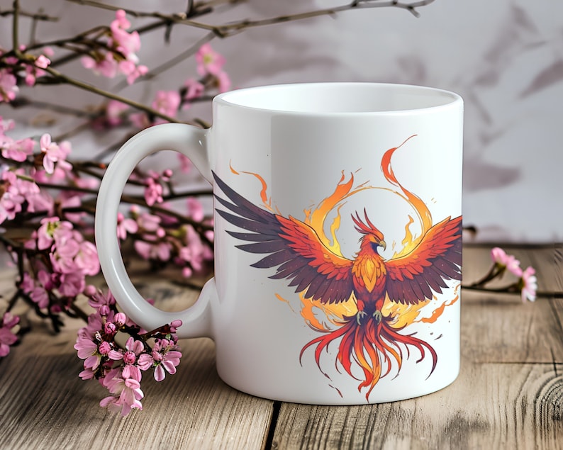 May include: White ceramic mug with a colorful illustration of a phoenix rising from flames. The phoenix is orange, red, and yellow with a white background.