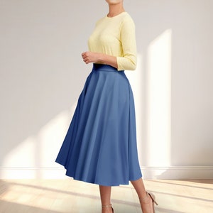 May include: A woman wearing a yellow top and a blue midi skirt. The skirt is a-line and has a high waist.
