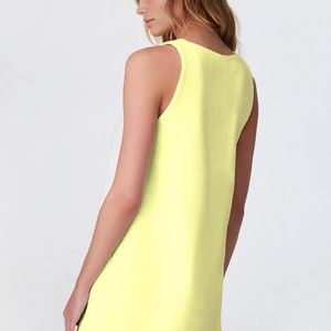 May include: A sleeveless, pale yellow mini dress with a scoop neck.