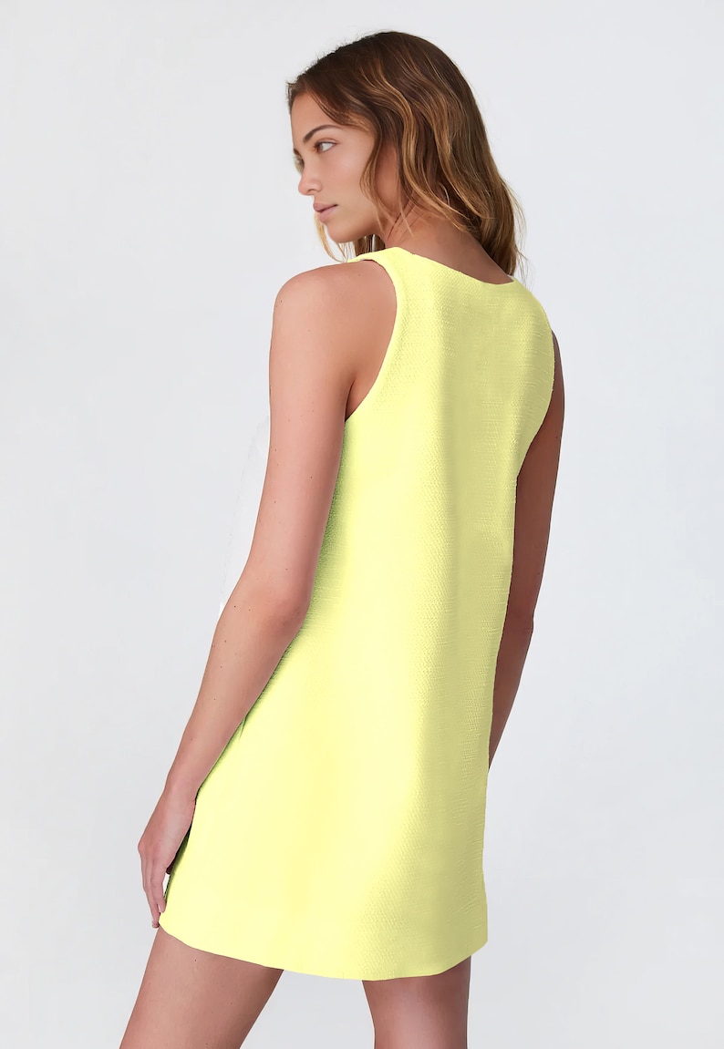 May include: A sleeveless, pale yellow mini dress with a scoop neck.