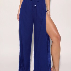 May include: Wide-leg pants with a high waist and a side slit on each leg. The pants are a deep blue color and have a drawstring waist.
