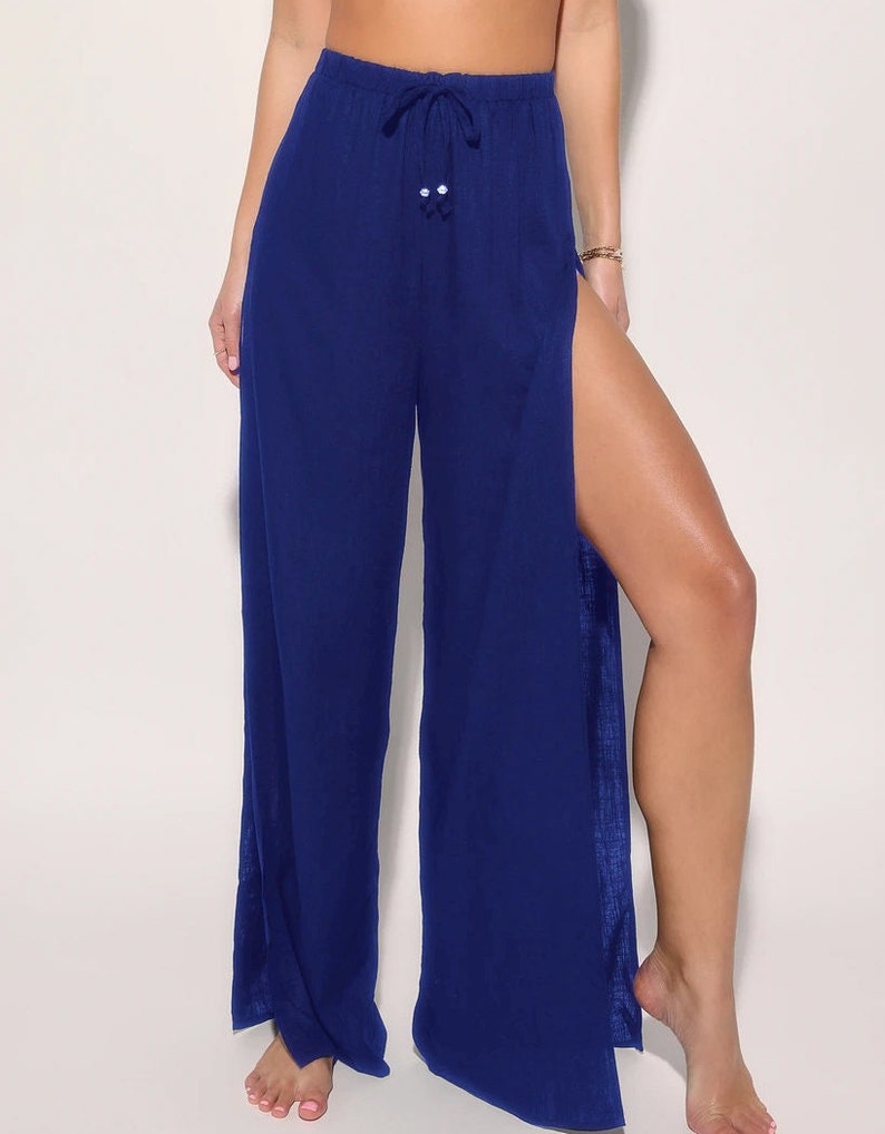 May include: Wide-leg pants with a high waist and a side slit on each leg. The pants are a deep blue color and have a drawstring waist.