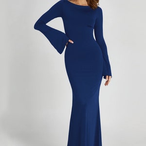 May include: A long-sleeved, dark blue maxi dress with a fitted bodice and a flowing skirt. The dress has a scoop neckline and bell sleeves.