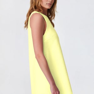 May include: A sleeveless, bright yellow mini dress with a scoop neck.
