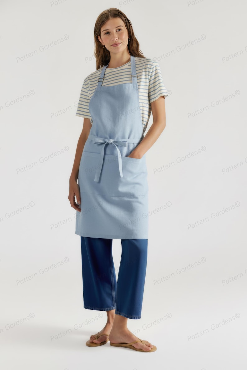 Puede incluir: Un delantal azul claro con un bolsillo delantero y un lazo en la cintura. El delantal se lleva sobre una camiseta a rayas y pantalones azules. El delantal est&aacute; hecho de una tela suave y duradera.