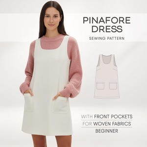 May include: A woman in a white pinafore dress with front pockets, worn over a pink sweater. The image features the text "PINAFORE DRESS SEWING PATTERN" and a dress outline. Text also reads "WITH FRONT POCKETS FOR WOVEN FABRICS BEGINNER".