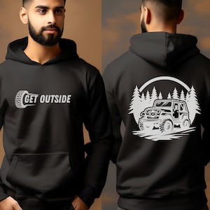 Puede incluir: Sudadera con capucha negra con un gráfico blanco de un jeep conduciendo por un bosque en la parte posterior y el texto "GET OUTSIDE" con un gráfico de neumático en la parte delantera.