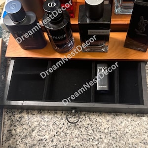 May include: A wooden box with a black velvet lined drawer. The drawer has multiple compartments for storing small items. The box is open and the drawer is pulled out. The drawer has a silver ring pull.