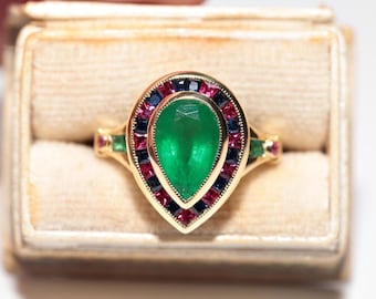 May include: A pear-shaped emerald gemstone ring set in gold with a halo of red and blue gemstones.