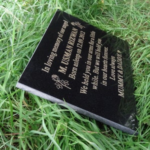 May include: Black granite memorial plaque with gold lettering. The inscription reads "In loving memory of our angel M. USMAN RIZWAN Born asleep on 12.09.2012 We held you in our arms for a little while. But we will hold you in our hearts forever. Love always MUMMY & DADDY."