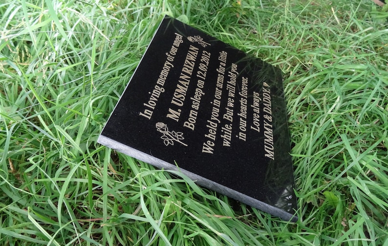 May include: Black granite memorial plaque with gold lettering. The inscription reads "In loving memory of our angel M. USMAN RIZWAN Born asleep on 12.09.2012 We held you in our arms for a little while. But we will hold you in our hearts forever. Love always MUMMY & DADDY."