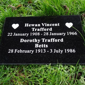 May include: Black granite headstone with white lettering. The inscription reads "Hewan Vincent Trafford 22 January 1908 - 28 January 1966 Dorothy Trafford Betts 28 February 1913 - 3 July 1986". Two white hearts are on either side of the inscription.