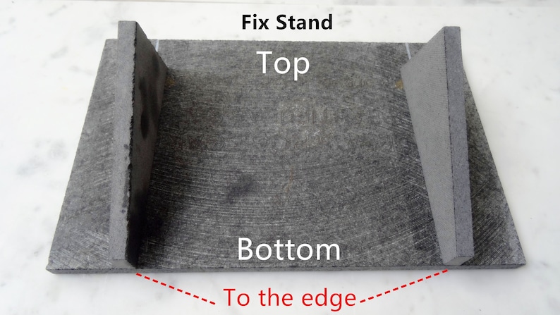 May include: A gray stone fix stand with two upright pieces on either side. The stand is labeled "Fix Stand", "Top", and "Bottom". A red dashed line points to the bottom edge of the stand and says "To the edge".