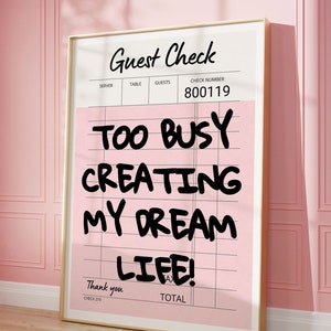May include: A pink and white guest check with the text "Too busy creating my dream life!" written in black marker. The check number is 800119.