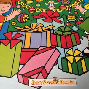 May include: A colorful illustration of a Christmas tree decorated with ornaments and garlands, surrounded by stacked gift boxes with bows. The scene includes cartoon characters and a label at the bottom that reads Little People Books.