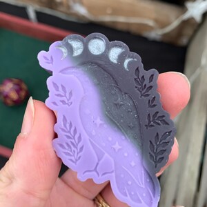 May include: Purple and black resin mold of a bird with a crescent moon design and stars. The mold is in the shape of a bird with its wings spread.