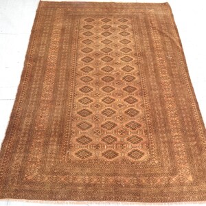 May include: A rectangular, brown rug with a central diamond pattern and detailed borders. The rug's color palette includes shades of brown and tan, creating a warm and inviting aesthetic. The rug is likely made of woven material.