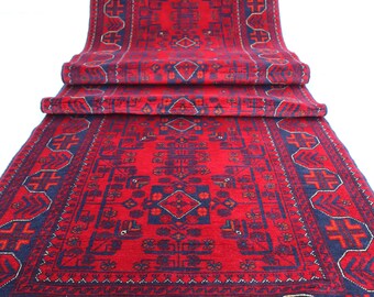 Op de afbeelding: Een rood en blauw patroonteppich met een franje rand. Het tapijt heeft een traditioneel ontwerp met geometrische vormen en bloemmotieven.