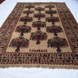 May include: A rectangular beige rug with a repeating pattern of stylized trees in vases. The trees have red, blue, and brown details. The rug has a detailed border with fringe along the edges.