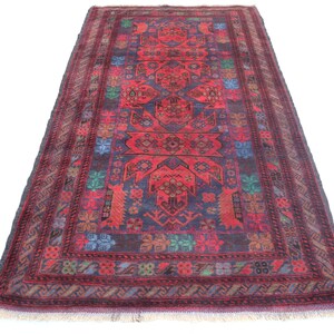 May include: A red, blue and green patterned rug with a geometric design. The rug has a fringed border.