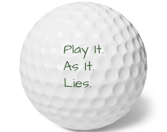Może przedstawiać: Biała piłeczka golfowa z dołeczkowaną powierzchnią. Na piłeczce zielonym kolorem wydrukowano tekst "Play It. As It. Lies.". Piłeczka golfowa ma standardowy rozmiar i kształt.