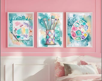 Op de afbeelding: Drie ingelijste aquarelprints met kunstbenodigdheden. Eén print toont een palet met verf, een andere penselen in een geometrische vaas en de derde een palet en penseelstreken. De prints hebben een turquoise en roze kleurenschema.